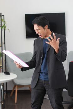 穿着黑色西装的男人在办公室里拿着文件，显得很沮丧