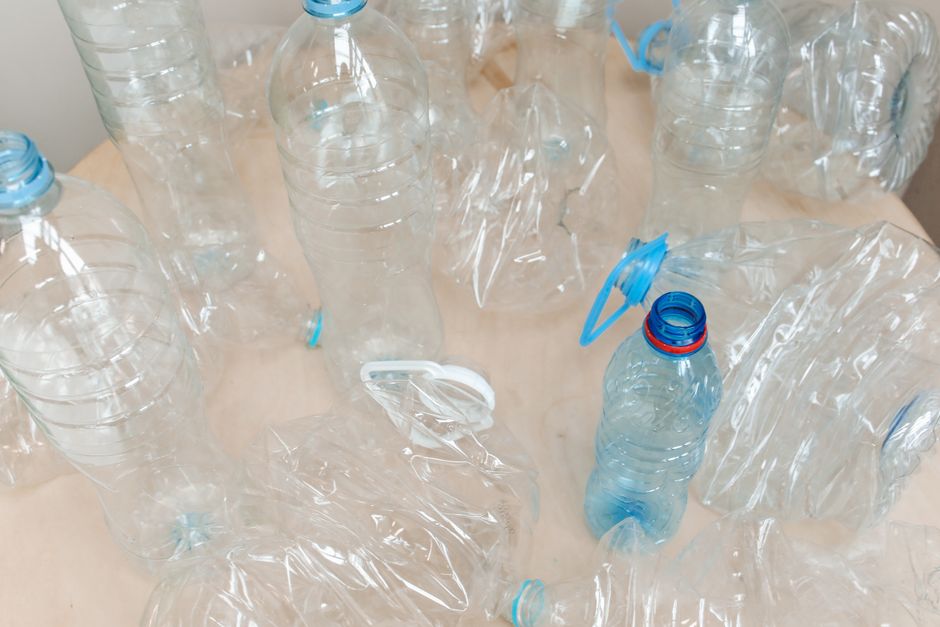 明るい木製の表面に並べられた空のプラスチックボトルの上からのビュー、リサイクルを強調。
