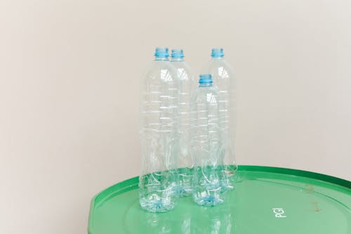 Close-Up Shot of Clear Plastic Bottles on Green Surface