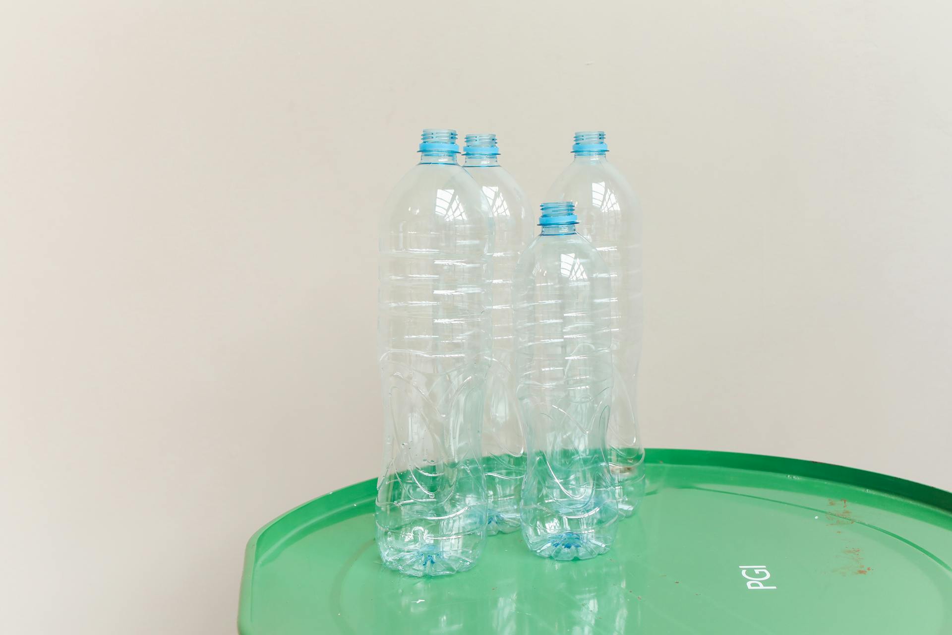Clear plastic bottles standing on a green drum, emphasizing recycling and sustainability.