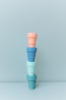 蓝色背景上，彩色可折叠杯子堆叠成列，展现出极简主义设计