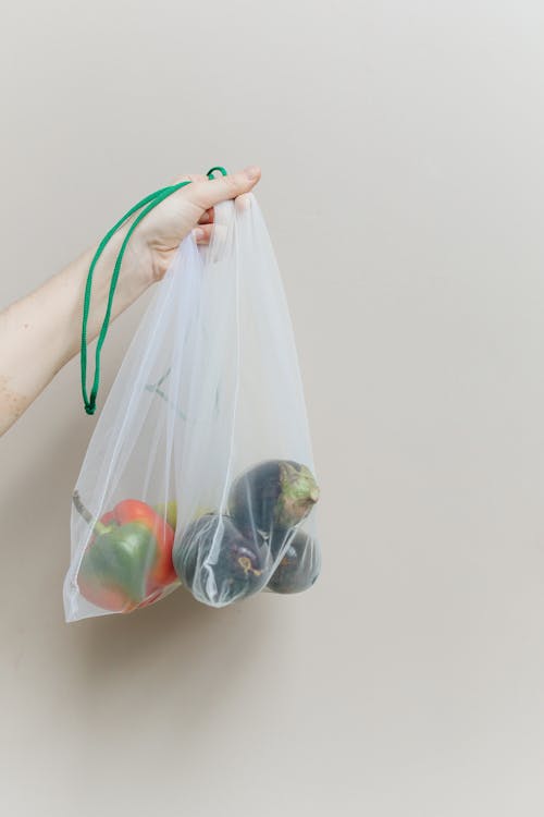 Close-Up Shot of a Person Holding a Reusable Bag with Vegetables