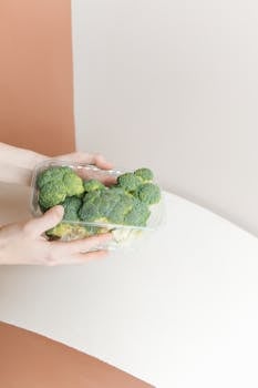 A person holding a plastic container with fresh broccoli, highlighting zero waste concepts.