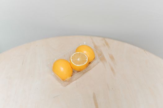 简约的柠檬被放置在木制表面的塑料托盘上，展现了新鲜与简洁的完美概念