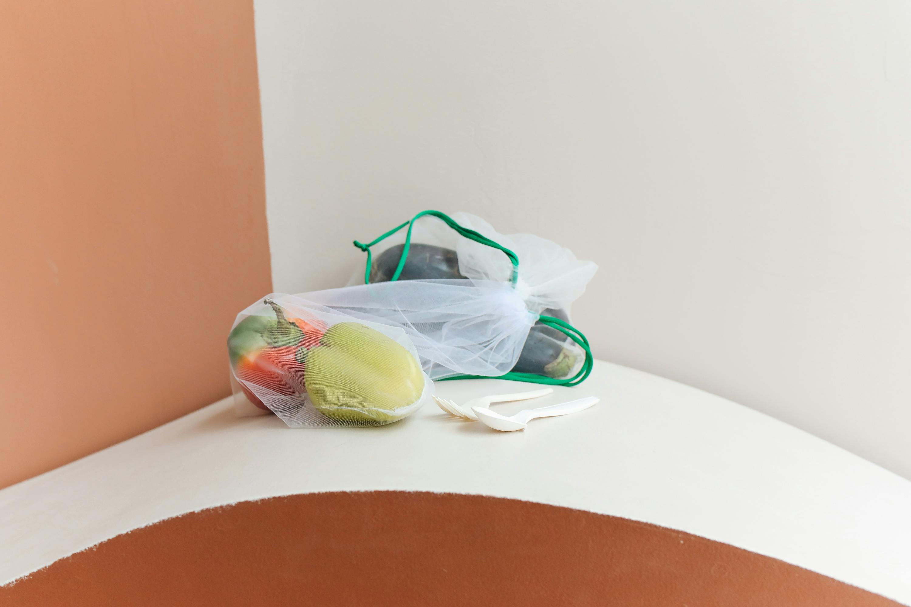 环保网袋里的彩色甜椒放在简约的桌子上