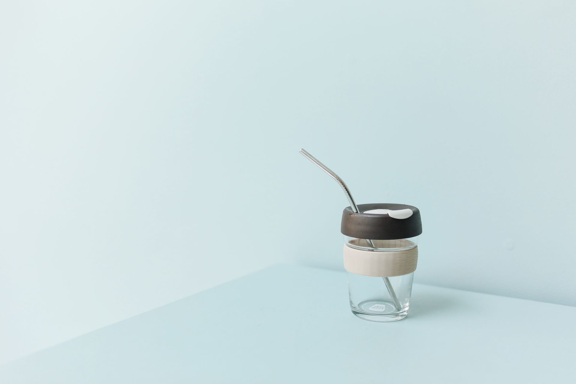 A stylish eco-friendly reusable cup with metal straw on a pastel background, promoting zero waste.