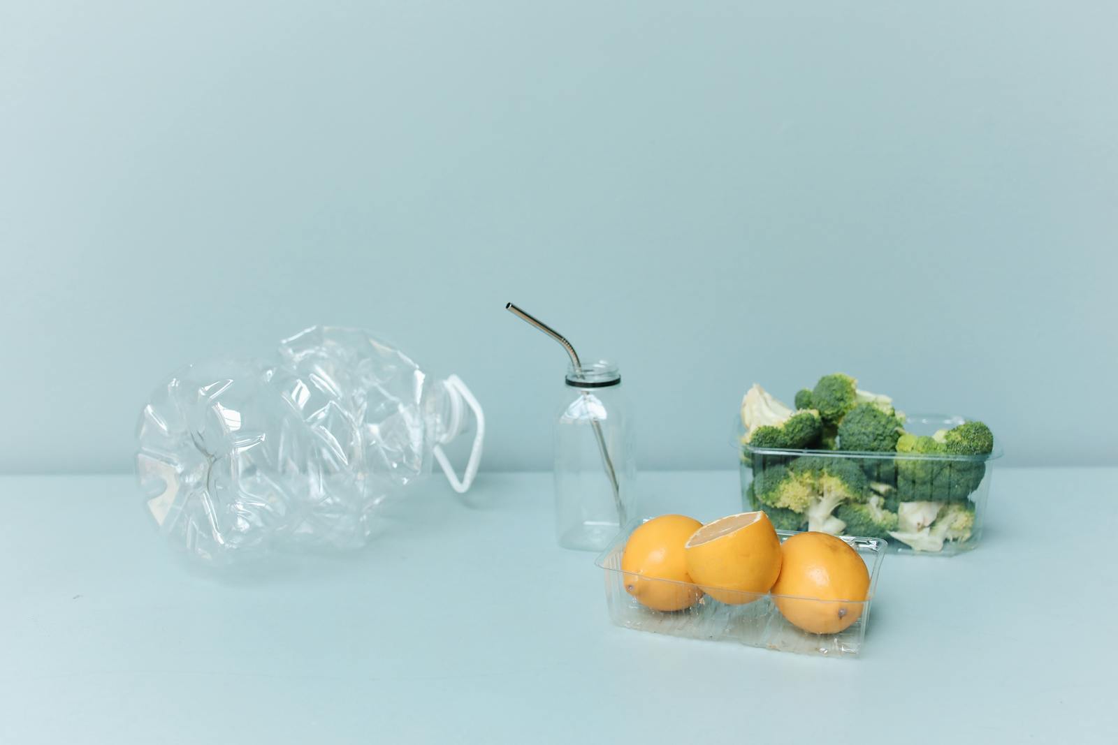 Lemons and Broccolis Inside Plastic Container Beside Plastic Water Containers