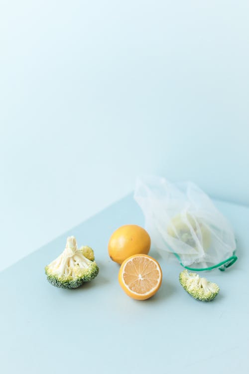 Close-Up Shot of Oranges and Broccoli on a White Surface