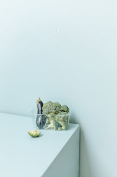 A minimalist composition with broccoli and eggplant on a white surface, highlighting fresh produce.