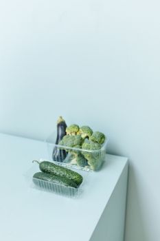 在干净的白色表面上，时尚地展示有机黄瓜和西兰花，完美诠释健康意识的生活