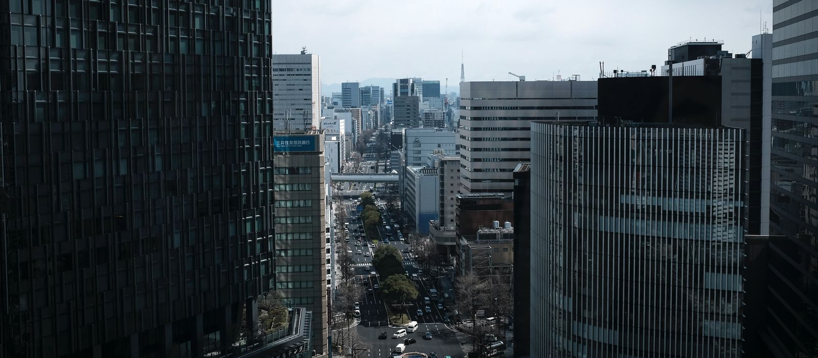 A bustling view of Nagoya's cityscape with tall buildings lining the streets on a cloudy day. — flights from Singapore to Nagoya