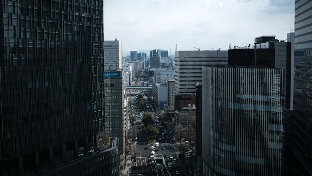 A bustling view of Nagoya's cityscape with tall buildings lining the streets on a cloudy day. — lounges at Nagoya Airport