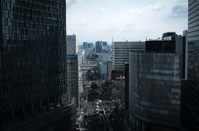 A bustling view of Nagoya's cityscape with tall buildings lining the streets on a cloudy day. — arriving in Tokoname