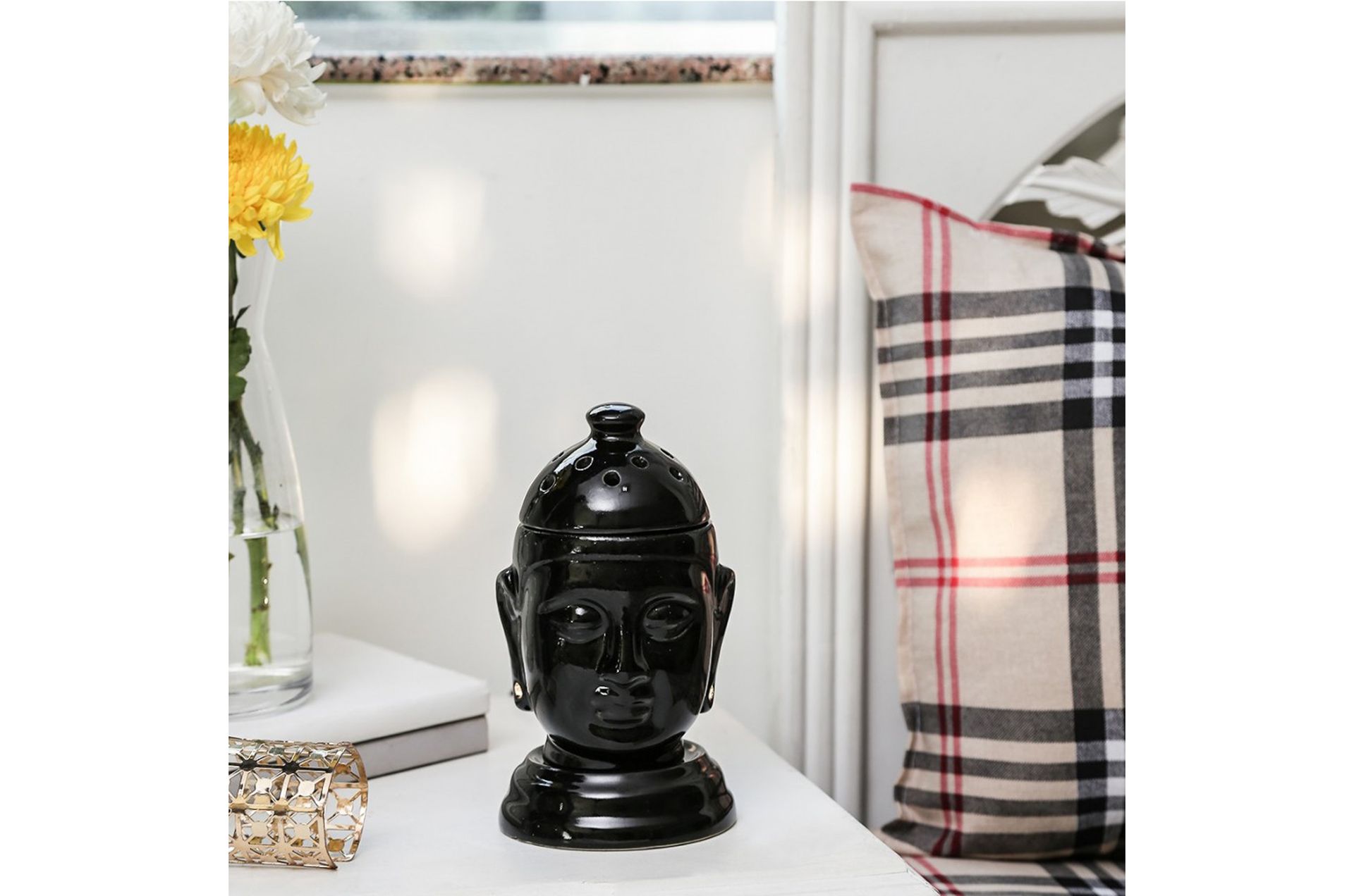 A serene black Buddha head figurine placed on a table with decorative elements, ideal for interior decor.