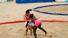 Young diverse female athletes fighting in sandy ring