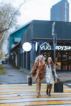 Fashionable women with shopping bags crossing an urban street on a cool day.