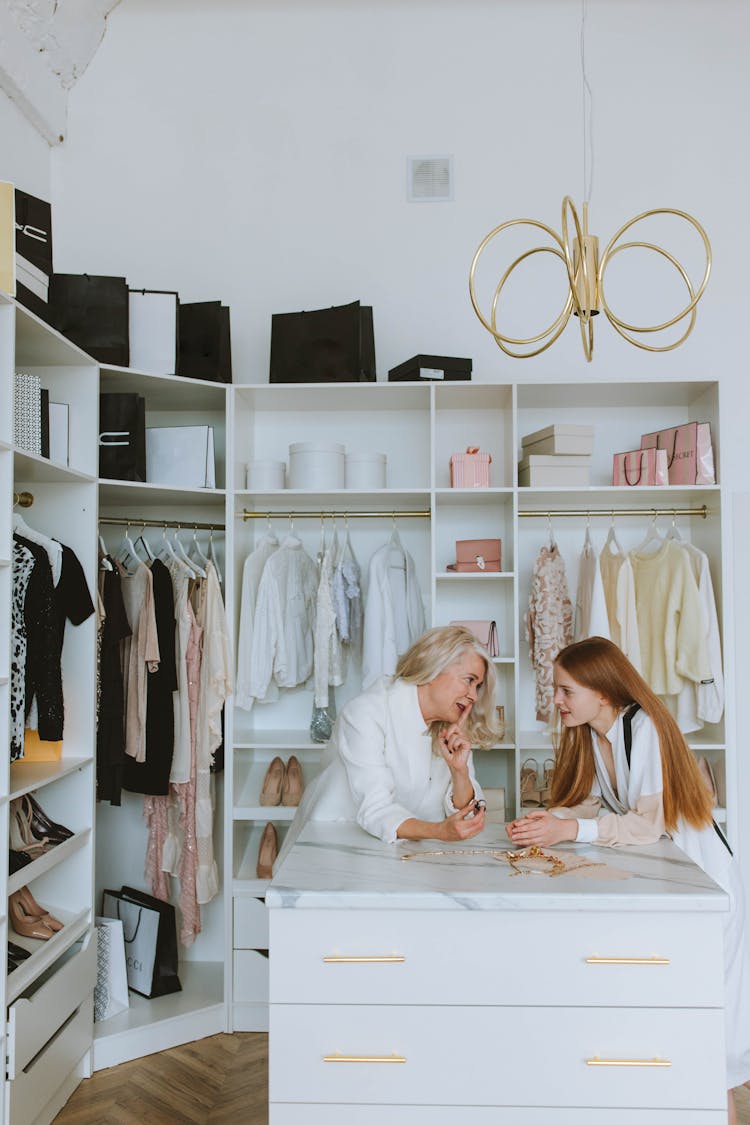 An Elderly Woman In White Long Sleeve Shirt Talking To A Woman In Walk-In Closet