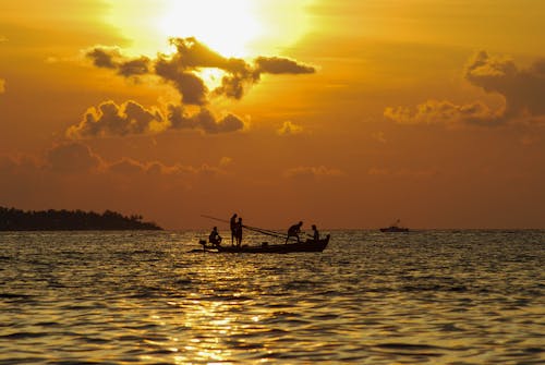 Free Silhouette of People on a Fishing Boat during Sunset Stock Photo