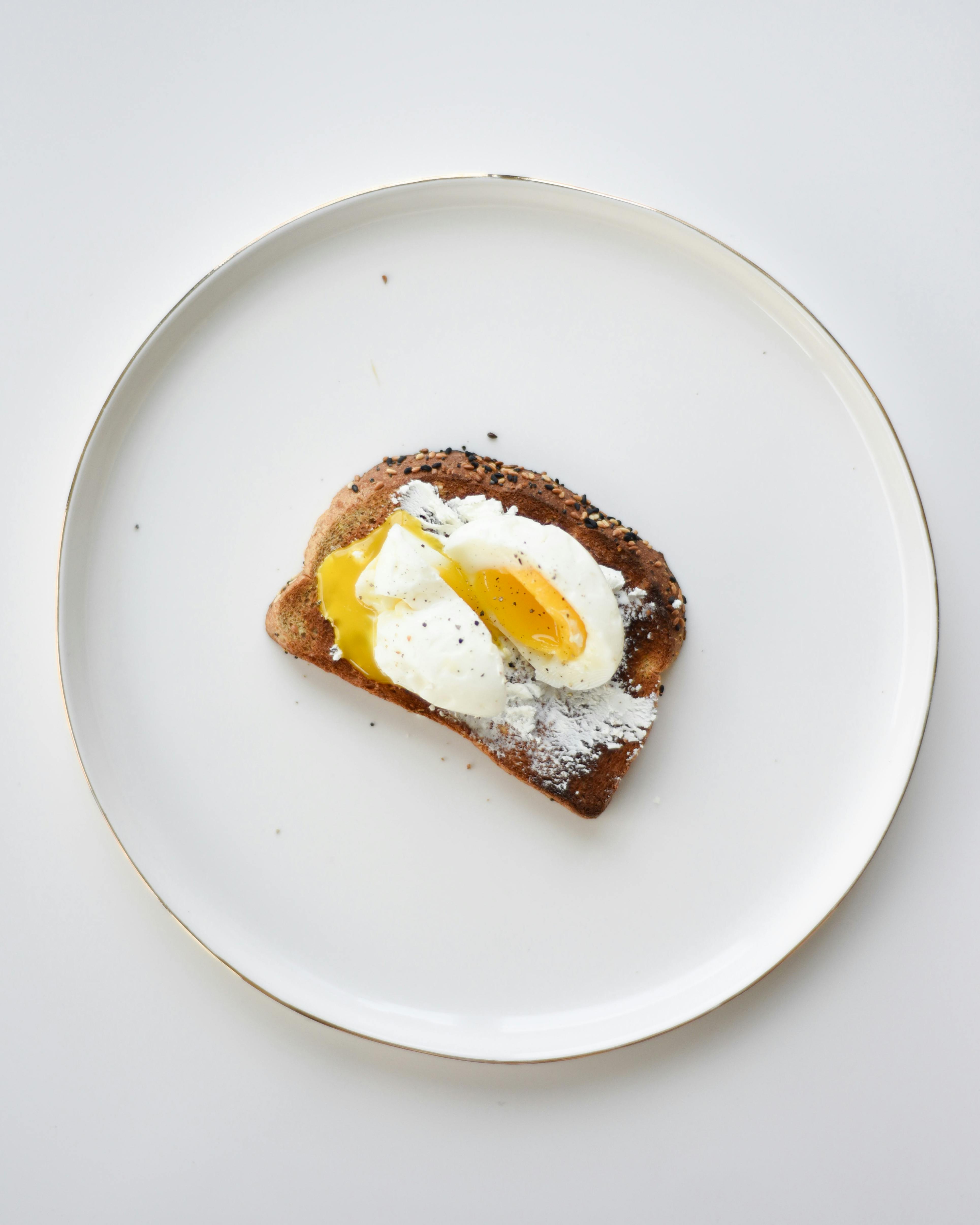 Delicious poached egg on artisan bread served on a minimalist white plate.