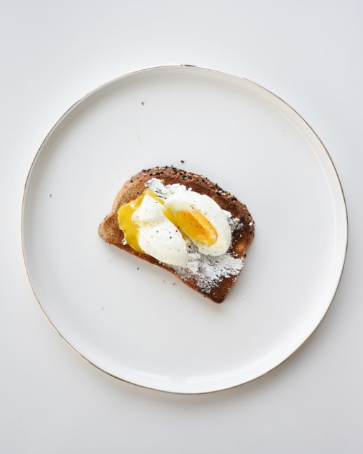 Delicious poached egg on artisan bread served on a minimalist white plate.