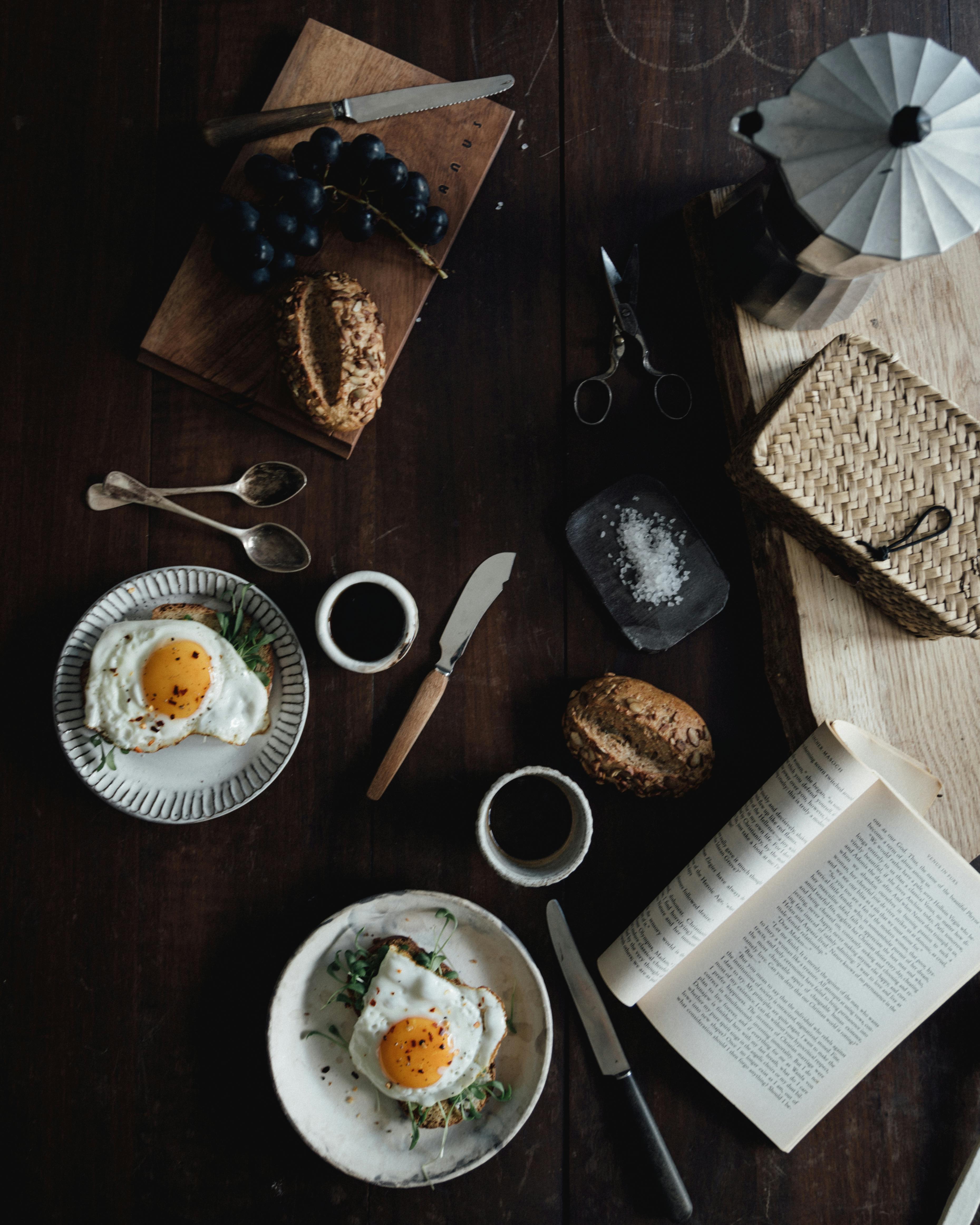 深色木桌上摆着乡村早餐：煎鸡蛋、面包和咖啡
