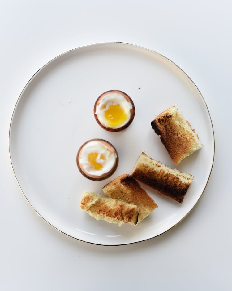 Close-Up Shot Of A Sliced Toasted Bread And Boiled Eggs On A White Plate