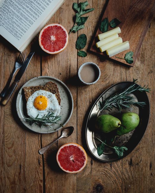 A beautifully arranged rustic breakfast with fried egg, grapefruit, and coffee on a wooden table.