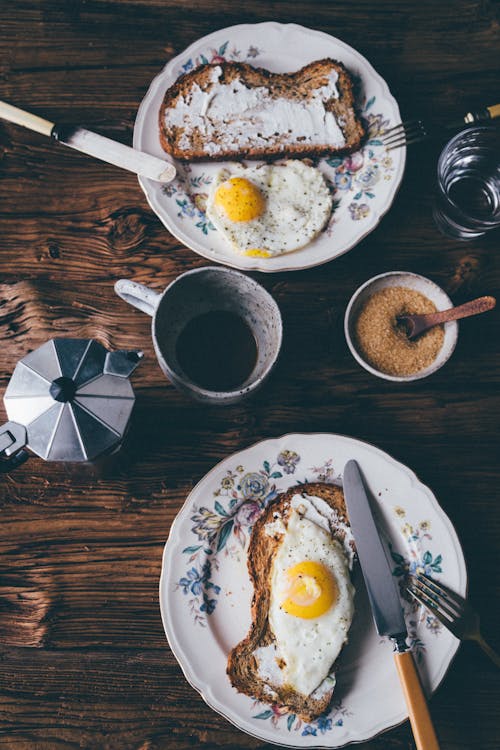 Telur Di Atas Roti Di Piring Keramik Putih Di Samping Mug Keramik Hitam Di Meja Kayu Coklat