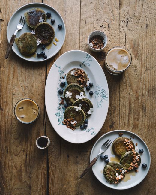 Aerial view of matcha pancakes with coffee on a rustic wooden table.