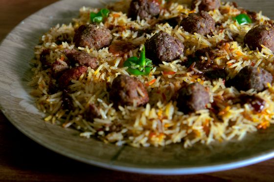 Plate of fluffy golden basmati pulao studded with browned spiced meatballs and green chilies