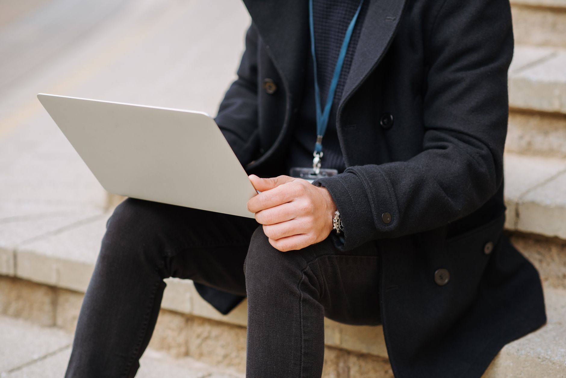 Crop anonymous male office employee in formal apparel with netbook working on project on street staircase
