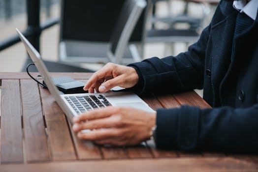 Blurred background of a businessman using a laptop outside on a wooden table.