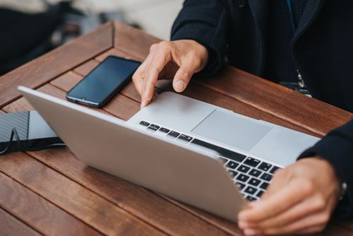 Free From above of crop anonymous male office worker with netbook and power bank at table in cafeteria Stock Photo