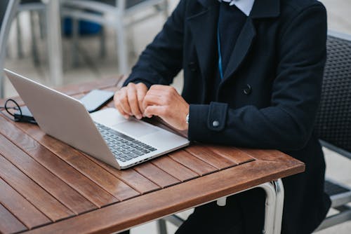 Free Faceless businessman with laptop at cafe table on street Stock Photo