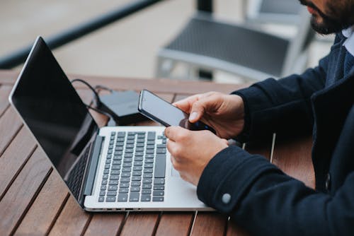 Free Crop executive chatting on smartphone at cafe table with laptop Stock Photo