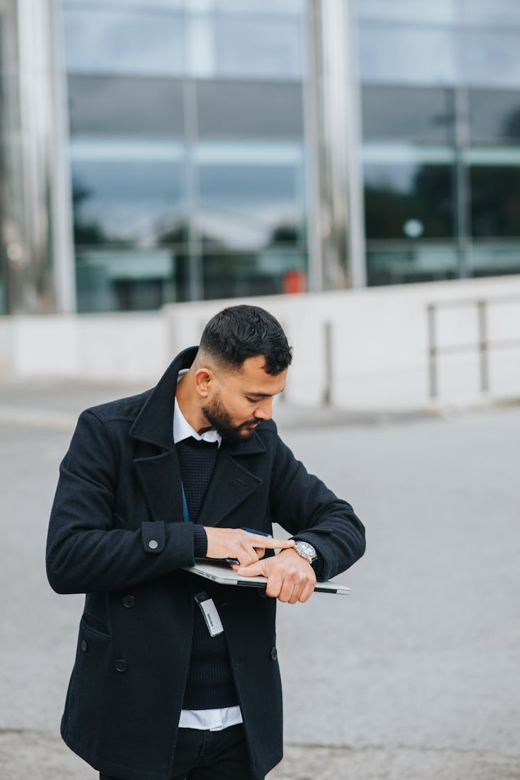 Ethnic Manager With Laptop Watching Time On Wristwatch In City