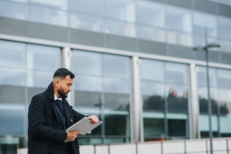 Serious Ethnic Manager With Laptop Checking Time In City