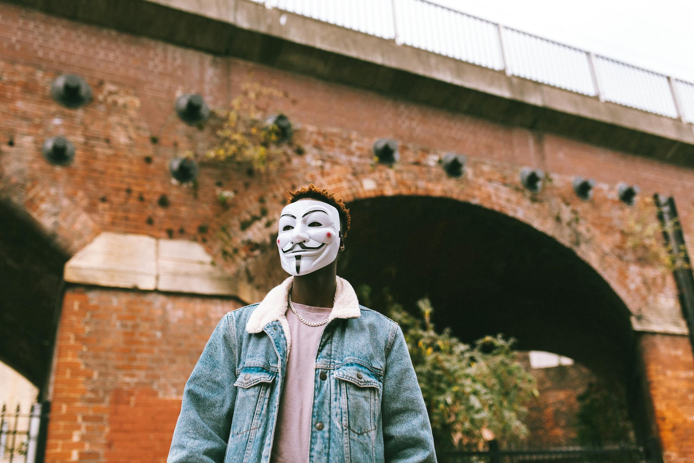 Man with mask in front of brick building
