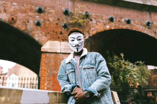 一个戴着盖伊·福克斯面具的男人在砖拱门前摆姿势