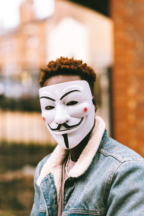 Free Black activist in Anonymous mask on city street Stock Photo