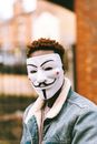 Black activist in Anonymous mask on city street