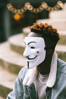 一个戴着盖伊·福克斯面具的神秘人物坐在户外台阶上