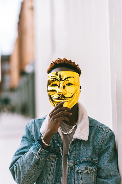 Black man covering face with Anonymous mask