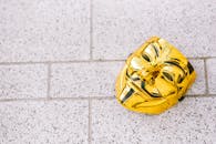 From above of colorful yellow anonymous mask representing protest symbol on rough walkway in daylight