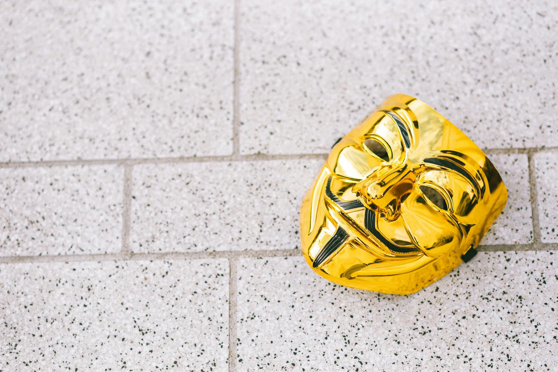 From above of colorful yellow anonymous mask representing protest symbol on rough walkway in daylight