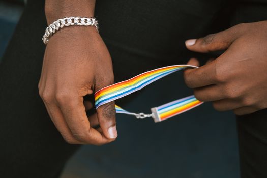 Crop unrecognizable black man holding pride bracelet