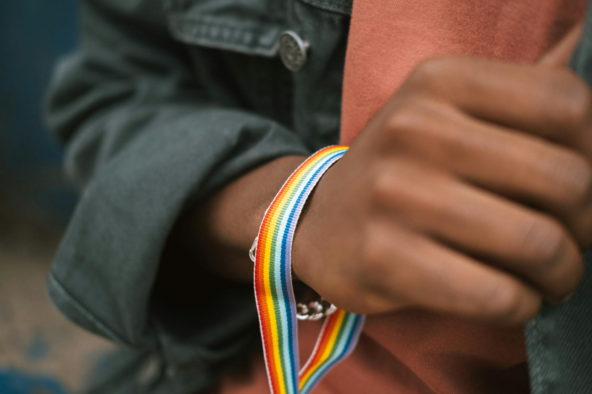 Close-up of a person's hand wearing a rainbow pride bracelet, symbolizing LGBTQ+ support and individuality.