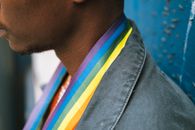Crop faceless black man wearing LGBT flag on neck