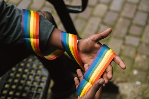 Crop faceless black gay wearing LGBT ribbon around arm