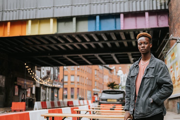 Black Man Standing Near City Bridge Painted In Rainbow Colors